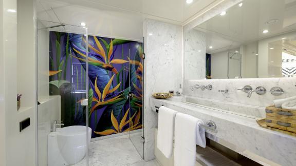 A colourful painting decorates the wall in the bright, simple marble bathroom of the luxury yacht.